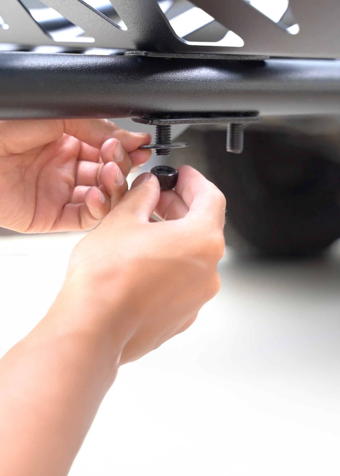 Installing a MotoTote tie-down arm and tire track using bolts and nuts, showcasing the replaceable and serviceable modular parts system built into MotoTote motorcycle carriers.