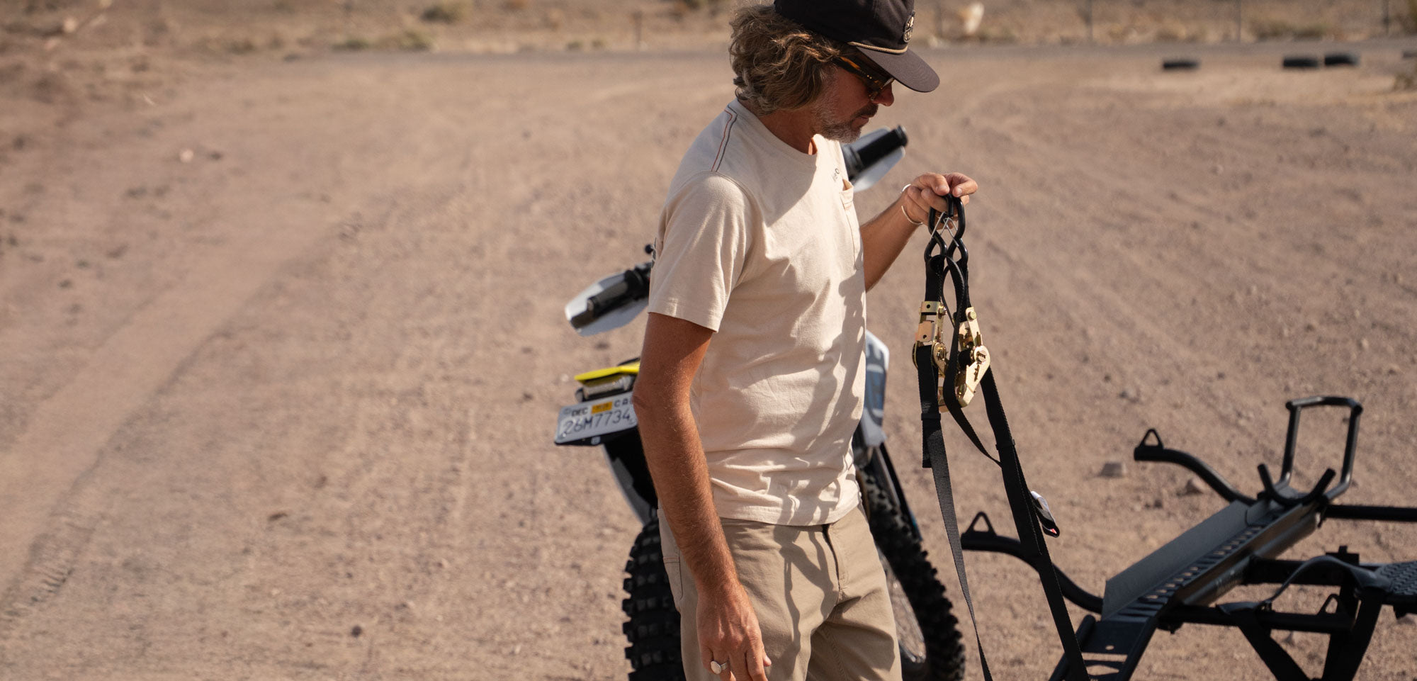 MotoTote SafeLoop ratcheting motorcycle tie-down straps being carried before securing a motorcycle onto a motorcycle hitch carrier for stable and reliable transport.