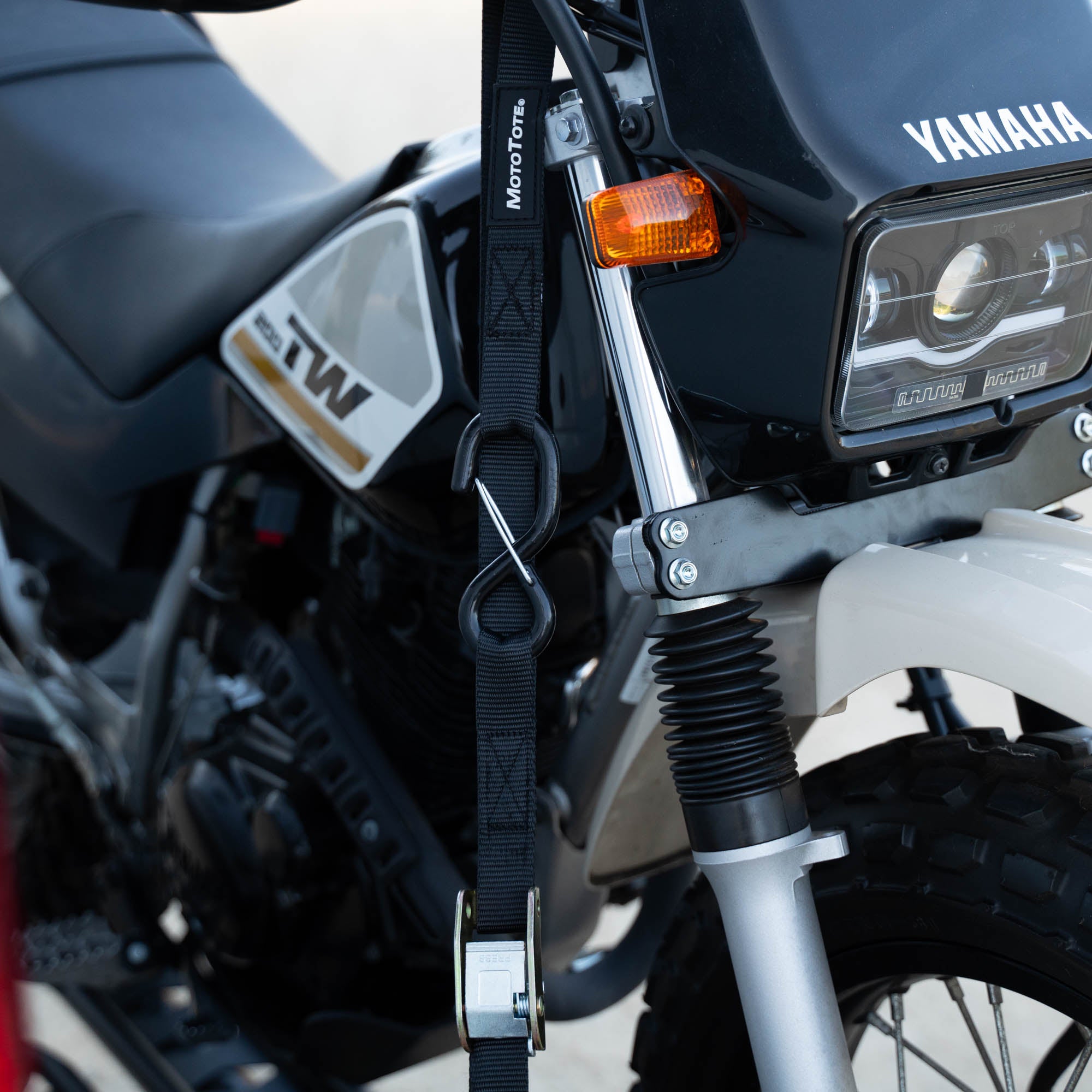 Yamaha TW200 motorcycle secured with MotoTote SafeLoop cam buckle tie-down straps on a motorcycle hitch carrier for stable and reliable transport.