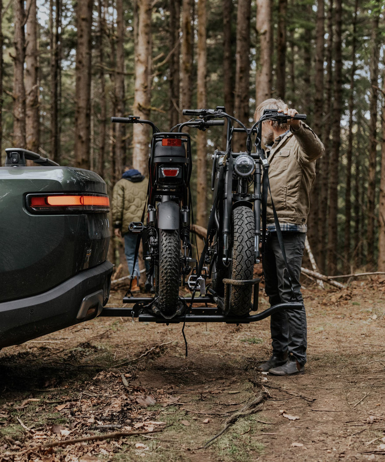 Rider loading two electric bikes onto a MotoTote Mini Dual electric bike rack attached to a Rivian, showcasing a secure bike rack for electric bikes and adventure-ready e-bike transport.