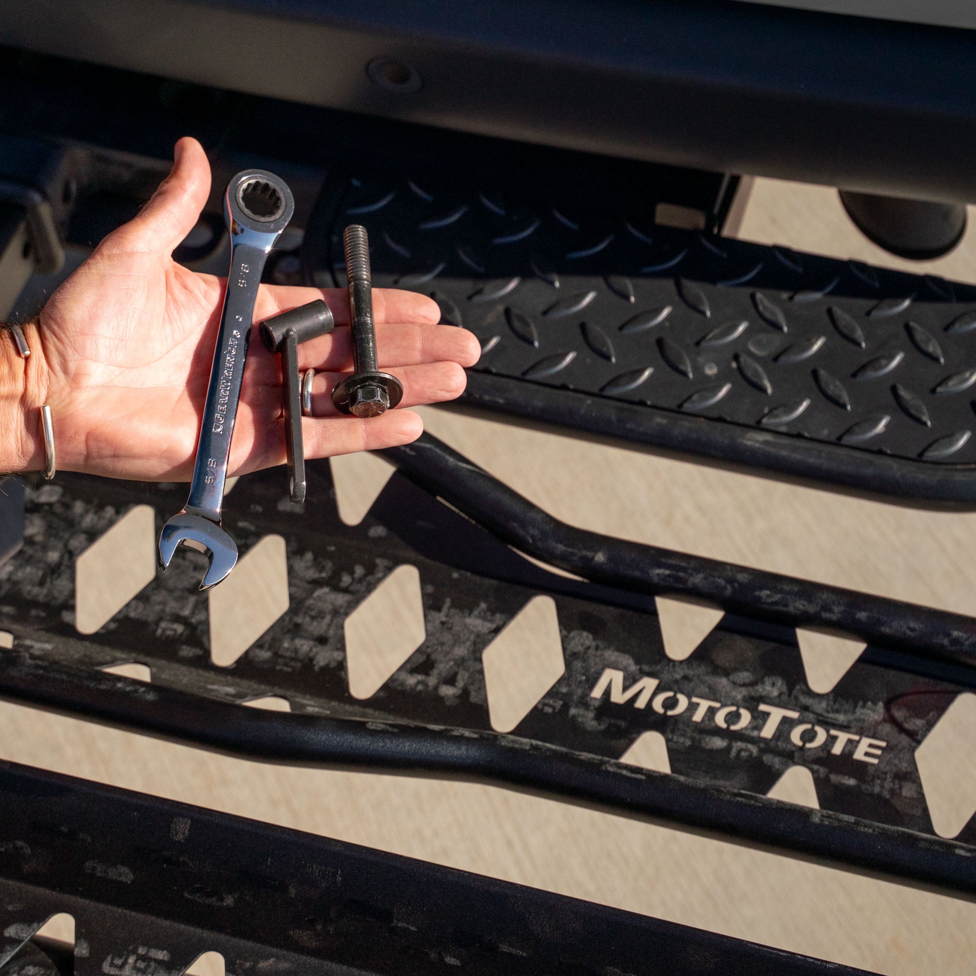 Rider holding a MotoTote ZeroWobble bolt designed to reduce movement and improve stability on any MotoTote motorcycle or electric bike carrier.