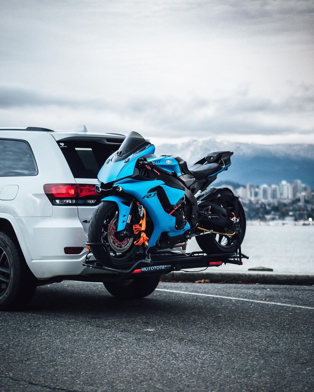 Blue Yamaha R1 sport motorcycle mounted on a MotoTote Sport motorcycle carrier attached to a Jeep Grand Cherokee, showcasing secure motorcycle transport with a premium hitch-mounted carrier.