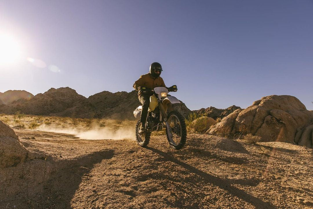 Dual sport rider exploring rugged desert terrain during an off-road adventure, inspired by the best destinations to travel with a MotoTote dirt bike hitch carrier.